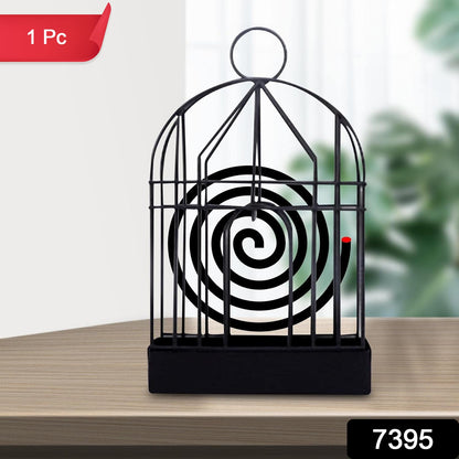 Iron birdcage mosquito coil holder placed on a rustic wooden table.