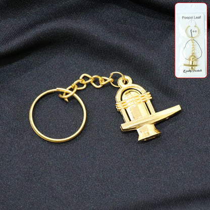 Golden Shivling metal keychain displayed on white background symbolizing spiritual devotion