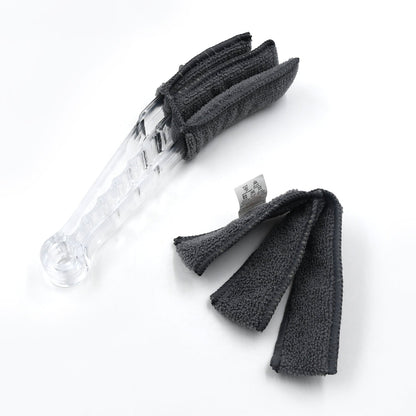 The compact blind cleaner brush being used to clean dust from a car's AC vent.