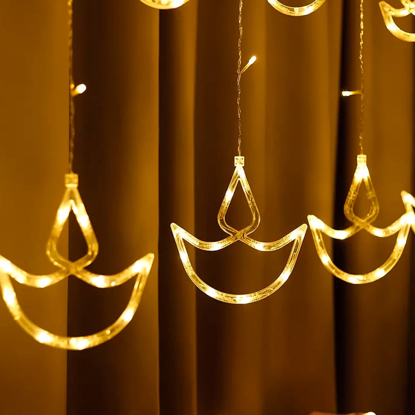 Full view of 12 Diya Curtain String Lights creating a warm glow in a home setting.