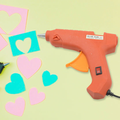 An electric hot melt glue gun with its power cord and a bundle of glue sticks on a clean surface.