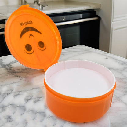 Compact round plastic lunch box showing its secure lid and vibrant design.
