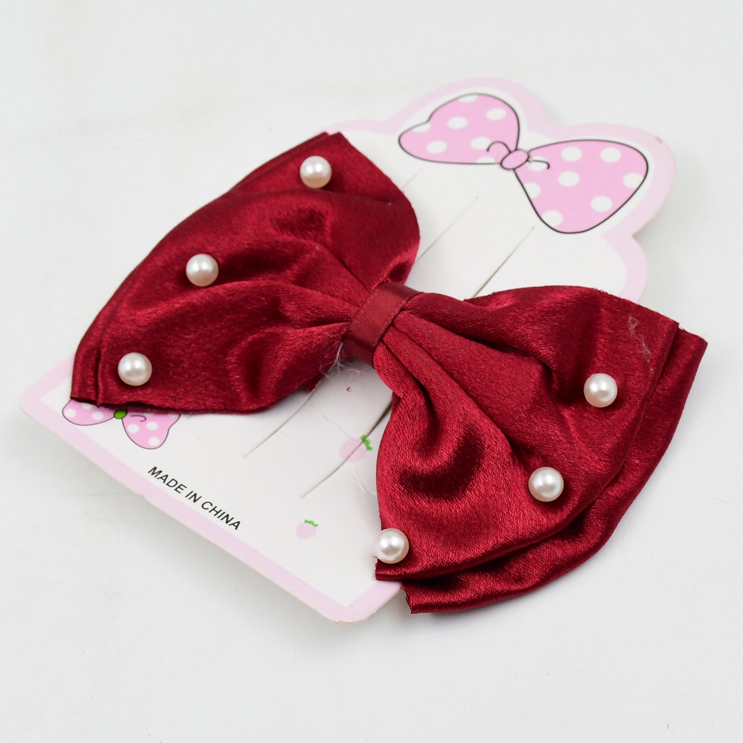 A young girl smiling while wearing a sparkly pink hair bow clip.