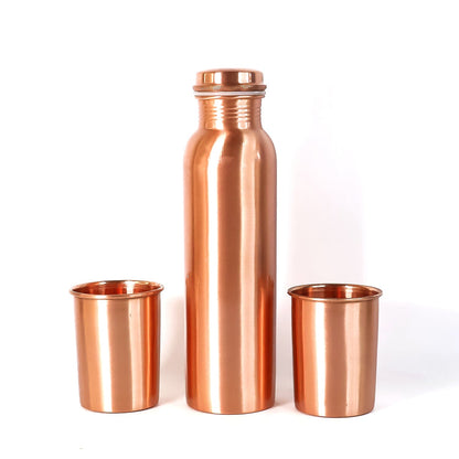 A person pouring water from the leakproof copper bottle into one of the matching glasses.