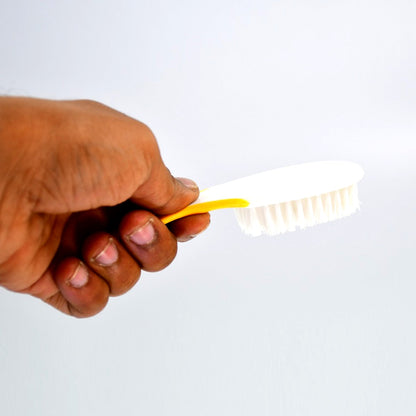 A hand using the Handle Grip Nail Brush to scrub fingernails, showing effective cleaning in action.