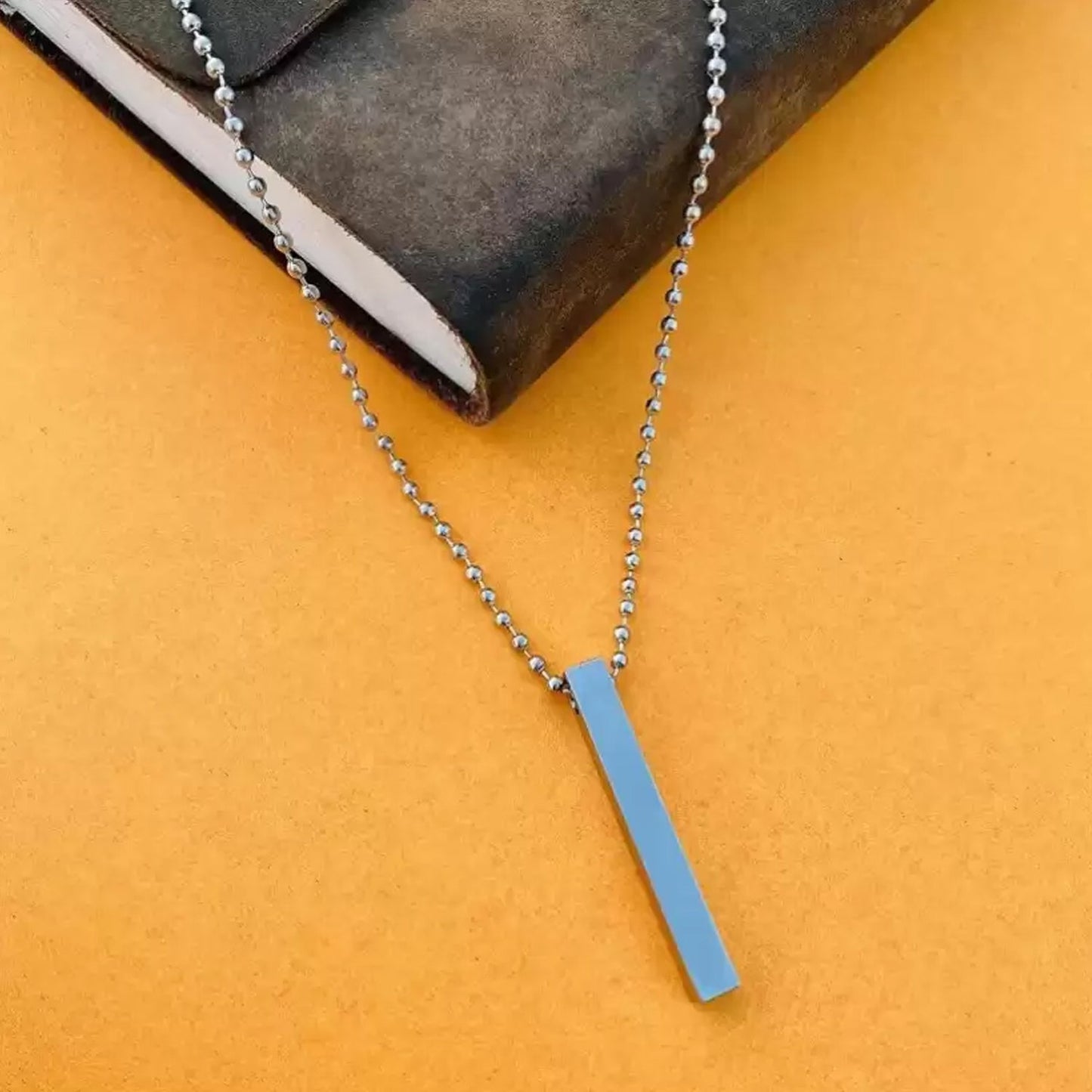 Detailed close-up of the polished stainless steel stick locket pendant.