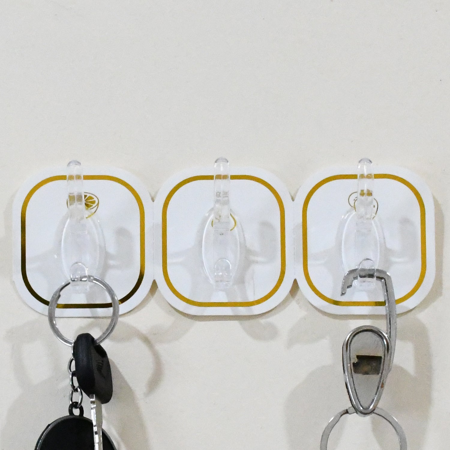 Hand applying a transparent adhesive hook onto a smooth wall surface for easy installation.