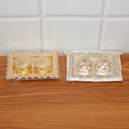 Hands holding the ornate rectangular pooja thali with flower-lid kumkum box