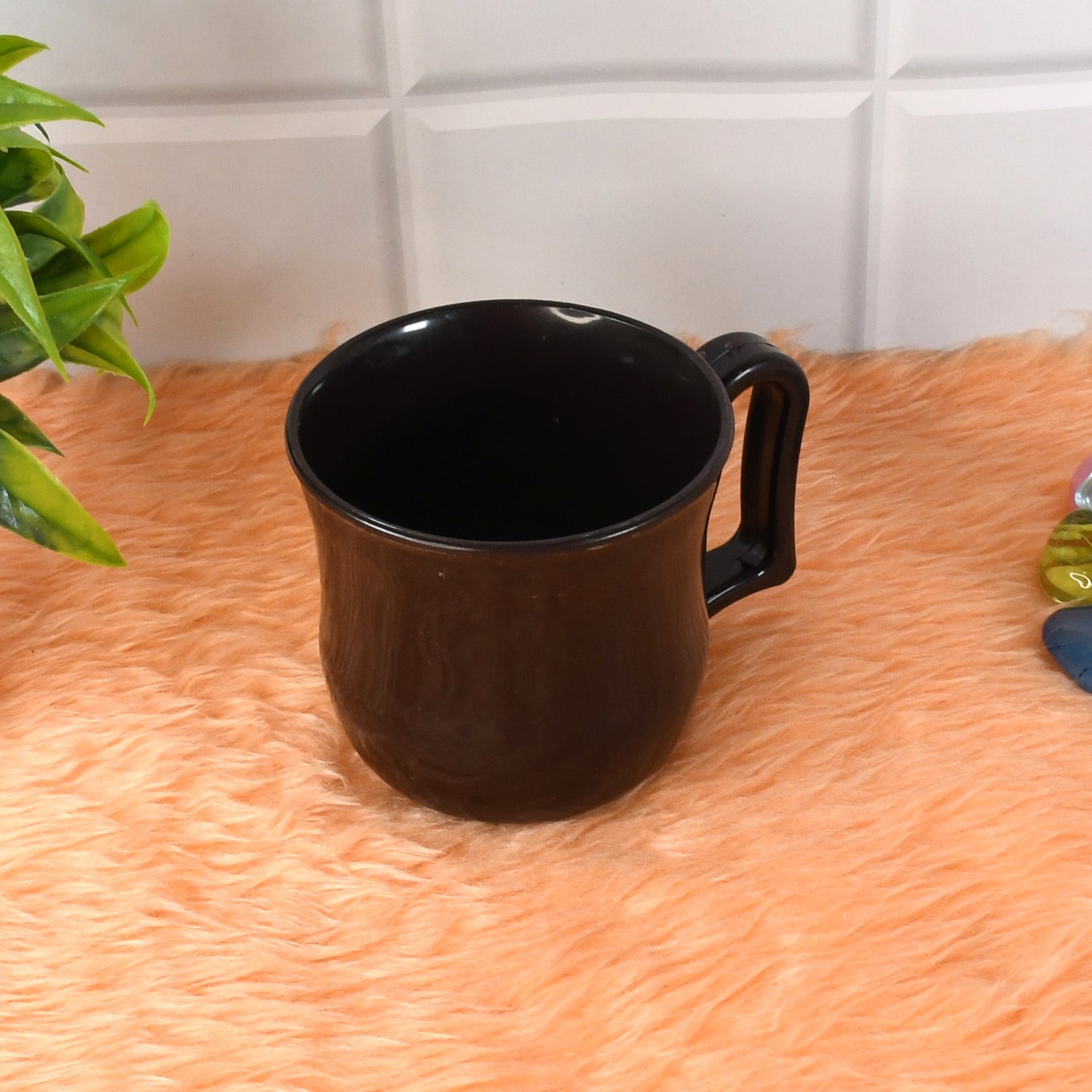 Stylish black plastic tea cup displayed alongside coffee beans, highlighting its versatility.