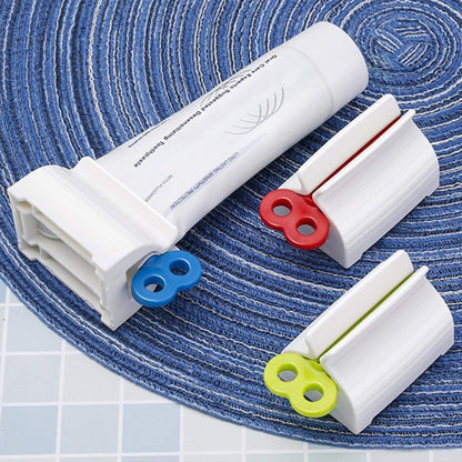 White toothpaste squeezer with an upright stand, holding a tube on a light surface.