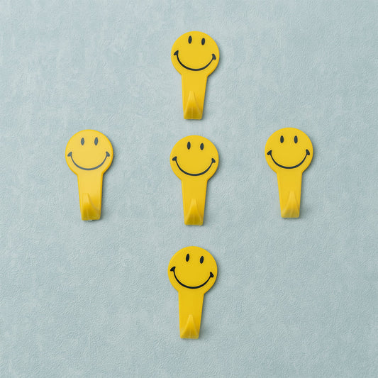 A set of five white self adhesive hooks displayed on a clean surface.