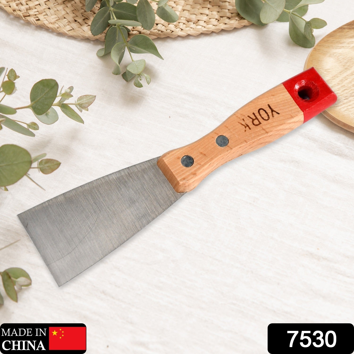 Hand holding a putty knife with its comfortable soft rubber handle.