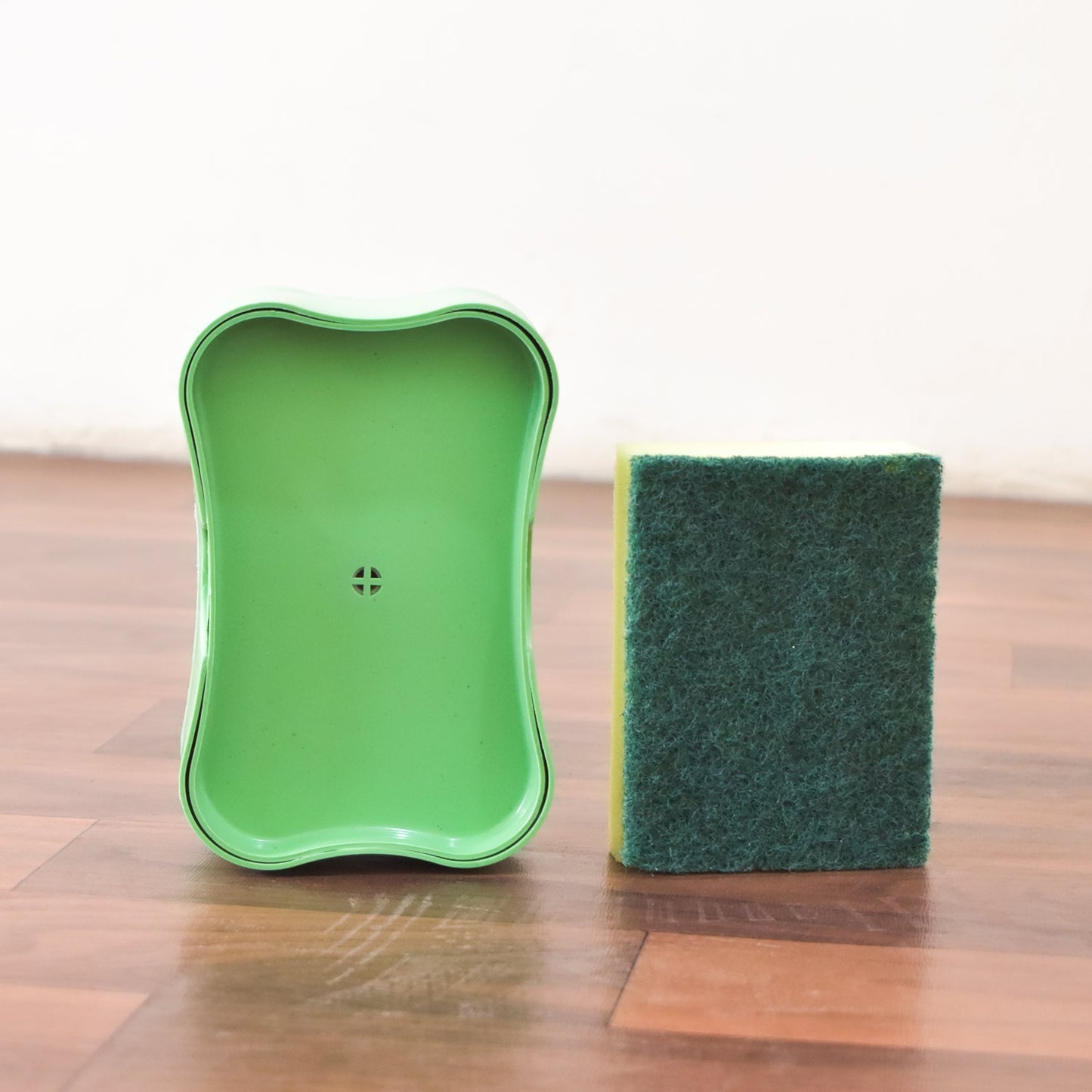 Plastic soap dispenser with integrated sponge caddy shown in a modern kitchen setting.