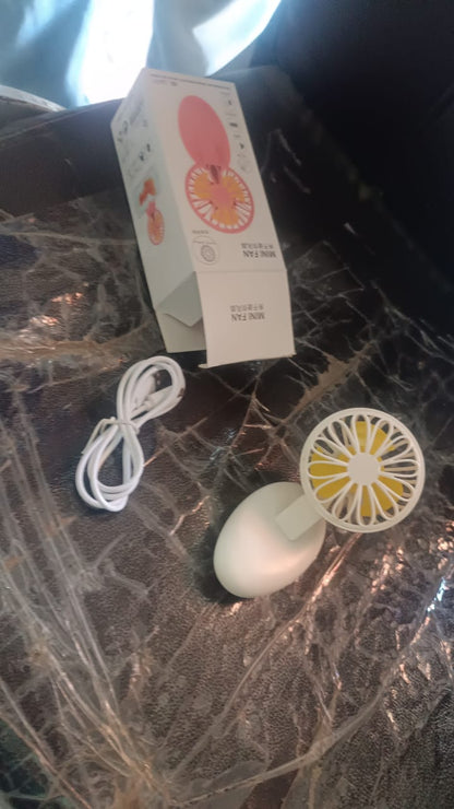A hand holding the compact Mini USB Handheld Fan, illustrating its portable size.