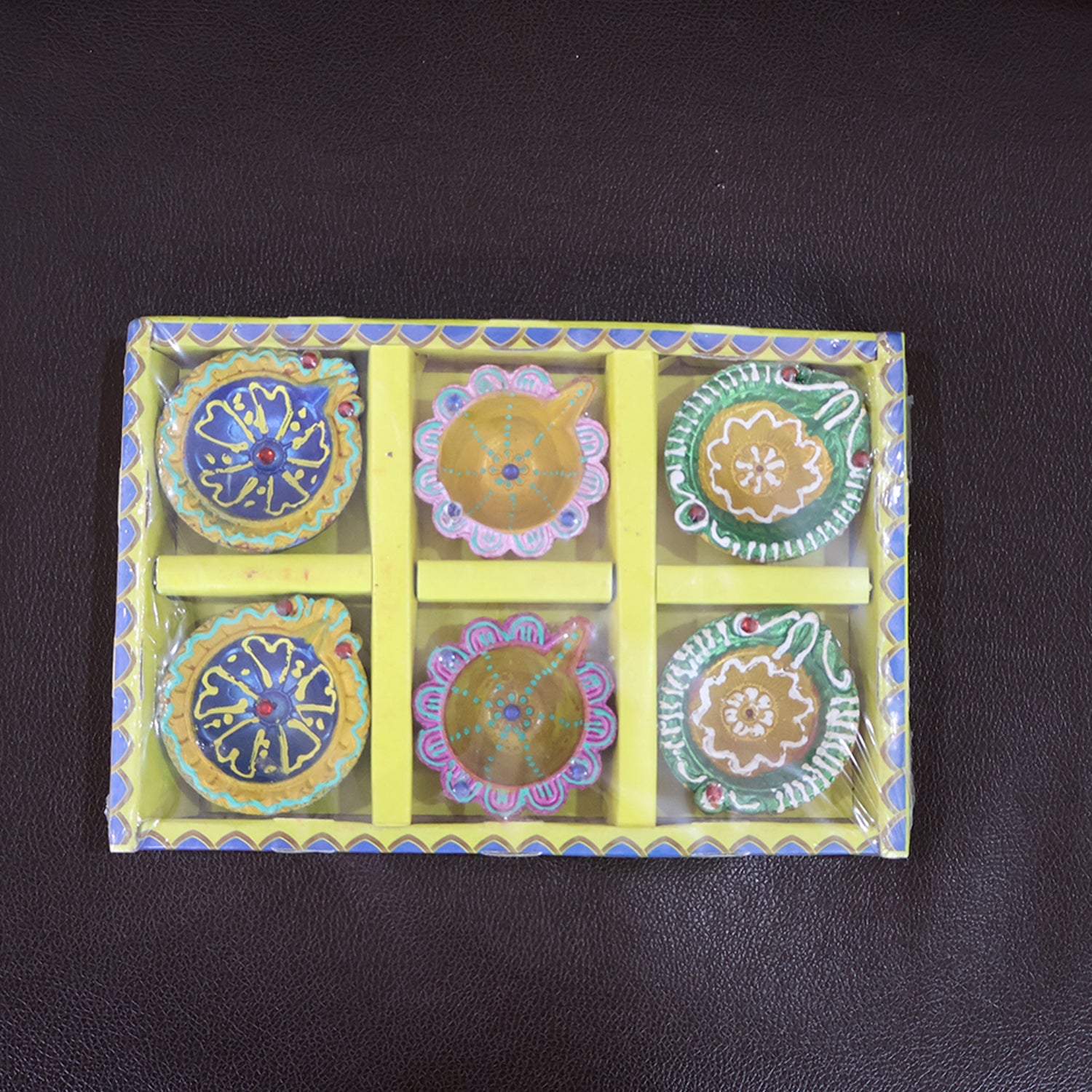 Brightly colored decorative clay diya with traditional motifs painted on it