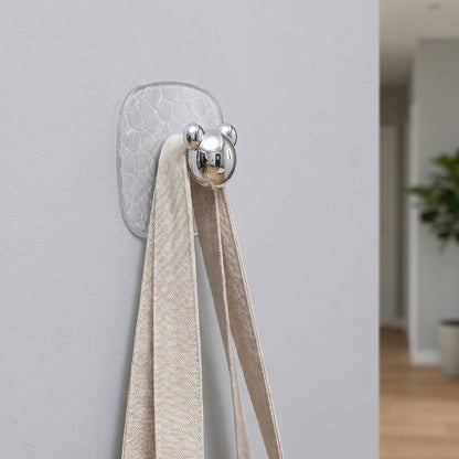 Clear plastic adhesive wall hooks organizing various household items neatly.