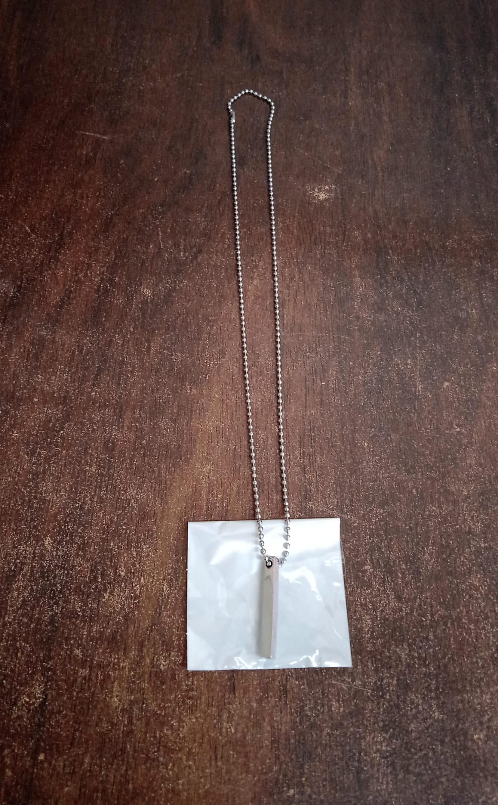 Stainless steel stick locket necklace displayed on a modern jewellery stand.
