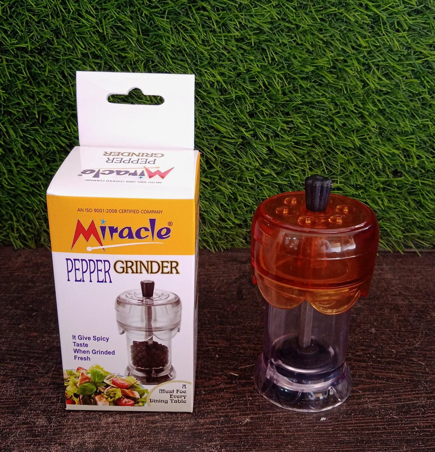 Transparent spice grinder adding freshly ground pepper to a dish.