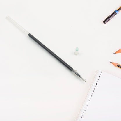 A single black pen refill lying on a surface, emphasizing its compact size.